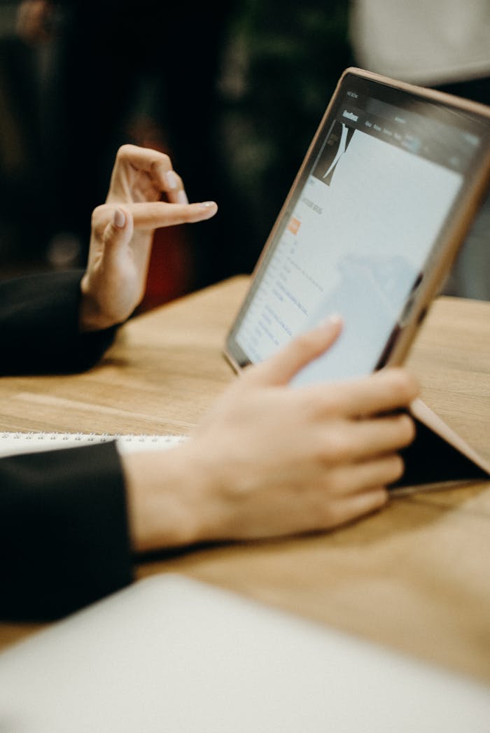 gallery-6 Close-up of hands working on a tablet in a sleek, modern office environment.
