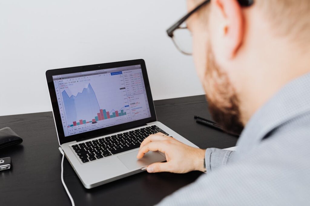 pexels photo 5717760 Man working on a laptop analyzing business data and financial graphs indoors.