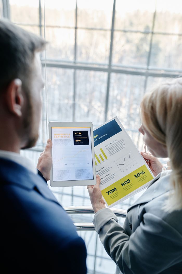Mastering the First Impression: Your intriguing post title goes here Two business professionals reviewing graphs and data on a tablet and paper report indoors.